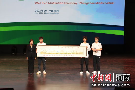 图为同学们向学校赠礼瓷板画作品《郑中学子走天下》。 郑州中学供图